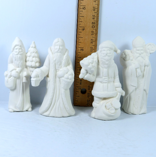 front view of handmade ceramic santa figurines for you to paint near a ruler showing t hem to be approximately 2 1/4 inches tall