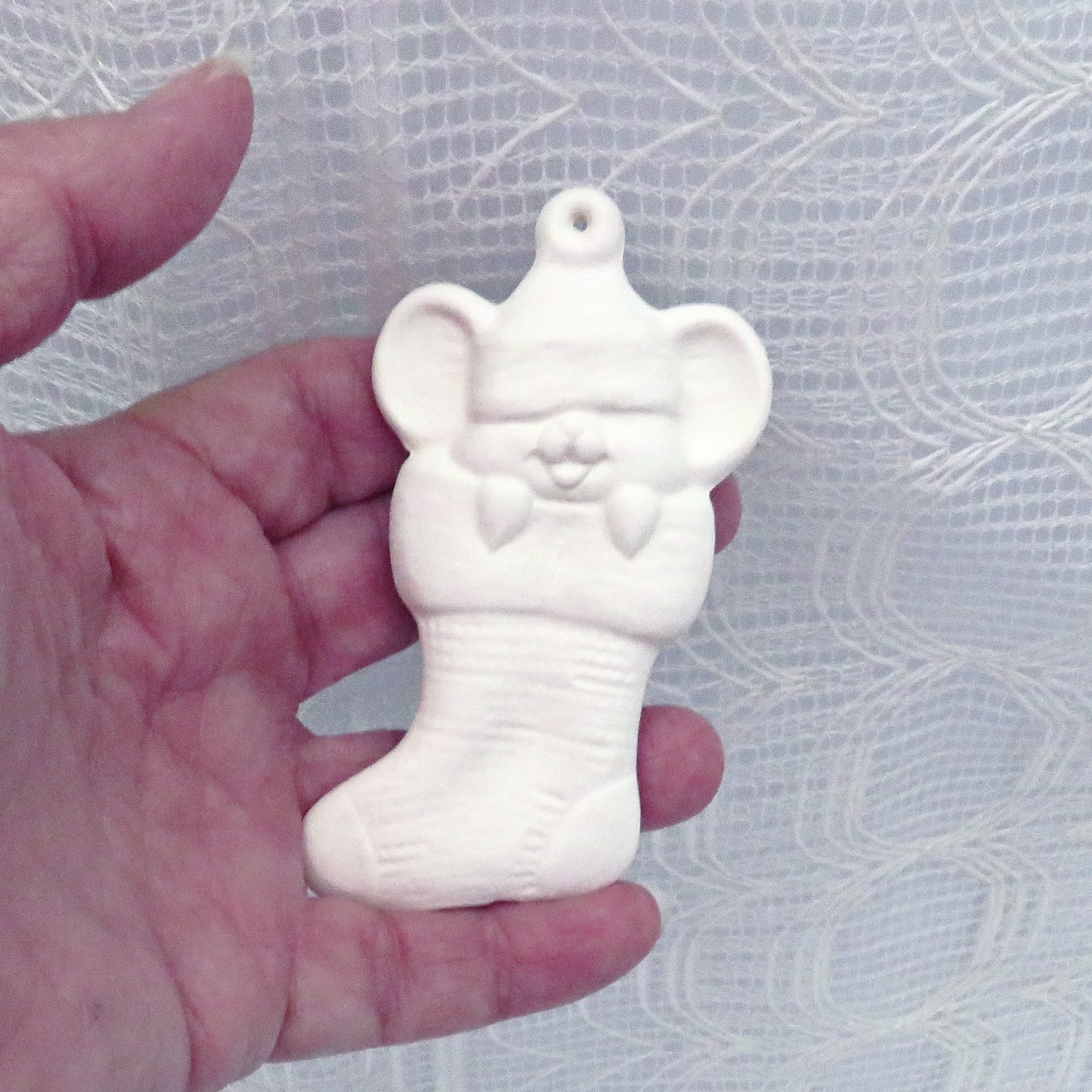 Ready to paint ceramic holiday ornament with mouse in Christmas stocking in my hand.