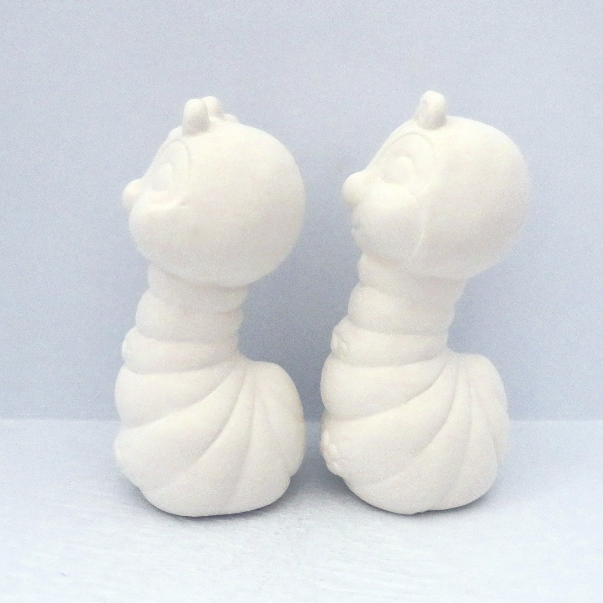 2 unpainted bisque bug statues side view on pale blue background