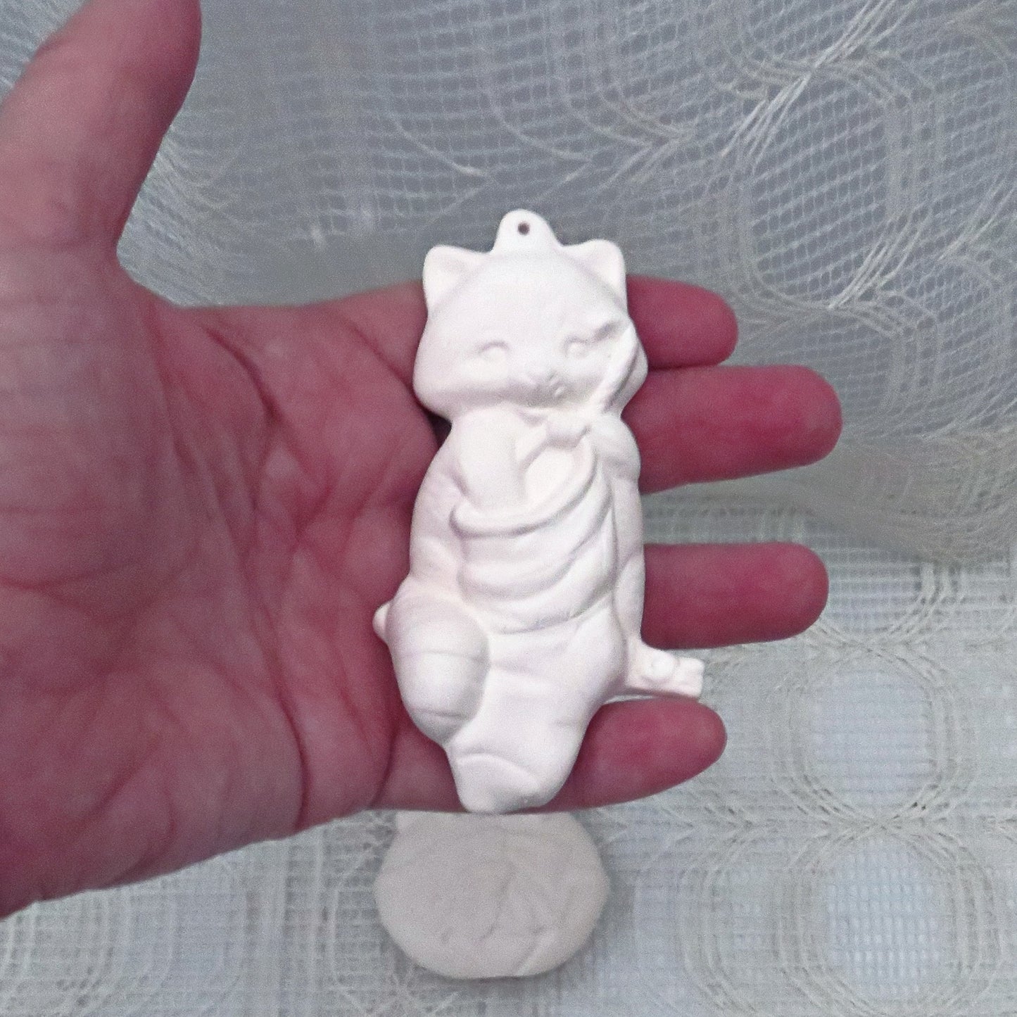Cat with paw in stocking unpainted ceramic ornament in my hand