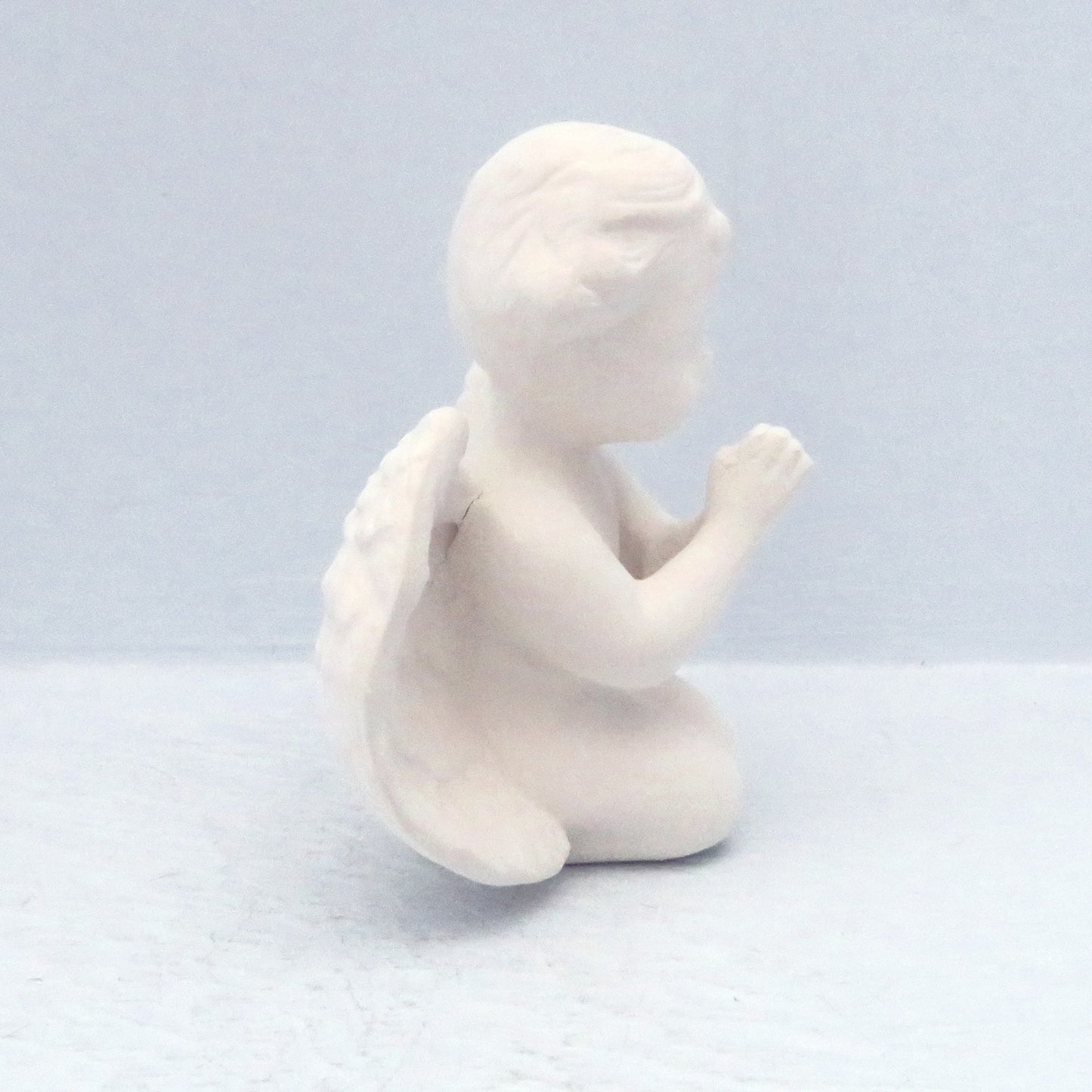 side vew of praying cherub on knees