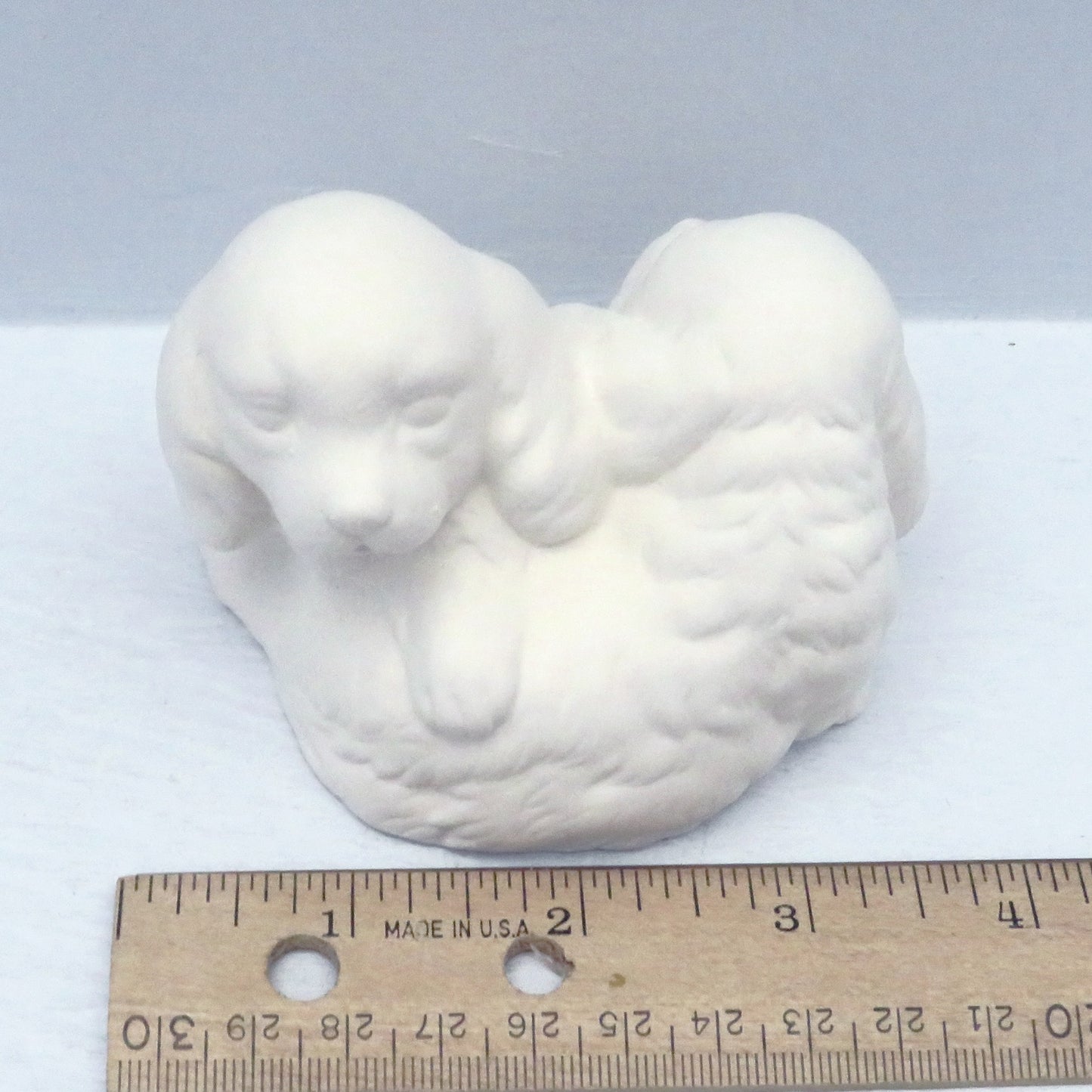 Handmade paint it yourself ceramic figurine with puppies near a ruler showing it to be approximately 3 3/4 inches wide