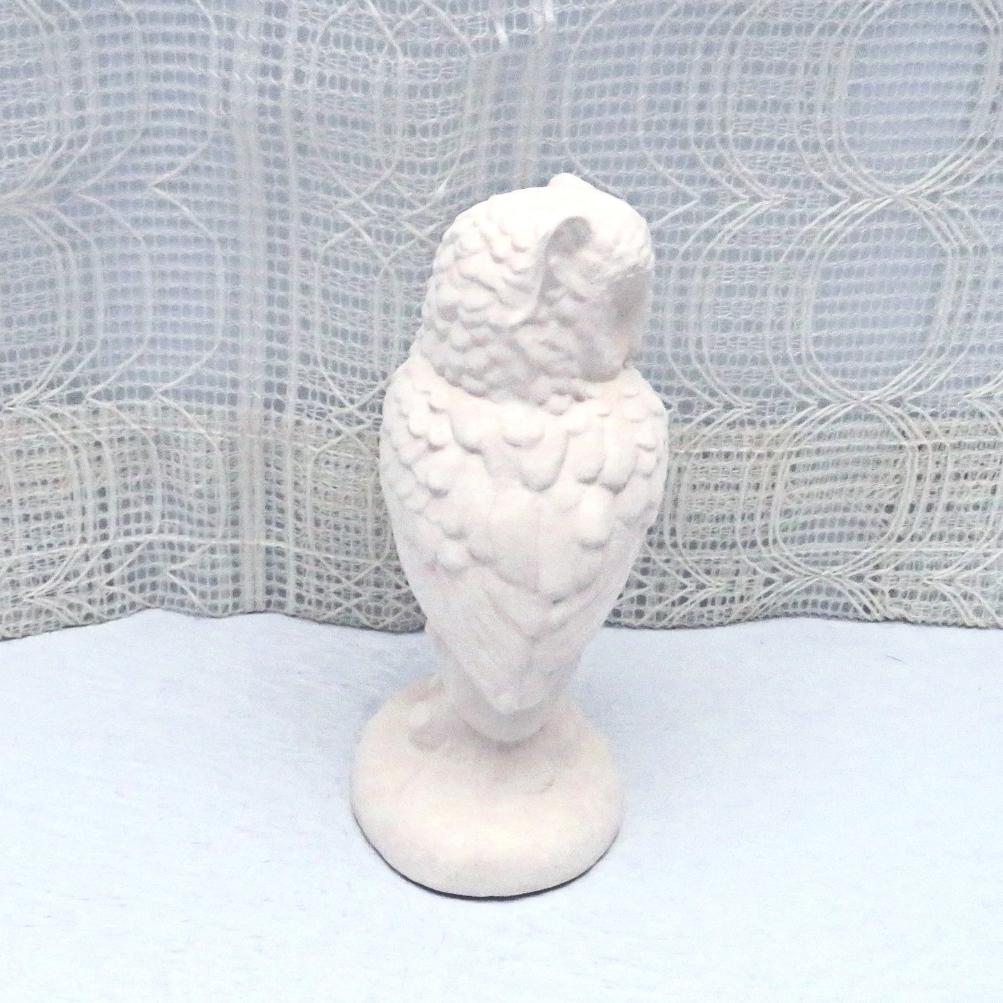 Rear view of paintable ceramic owl figurine showing the detail in the feathers. Its head is turned toward the right.