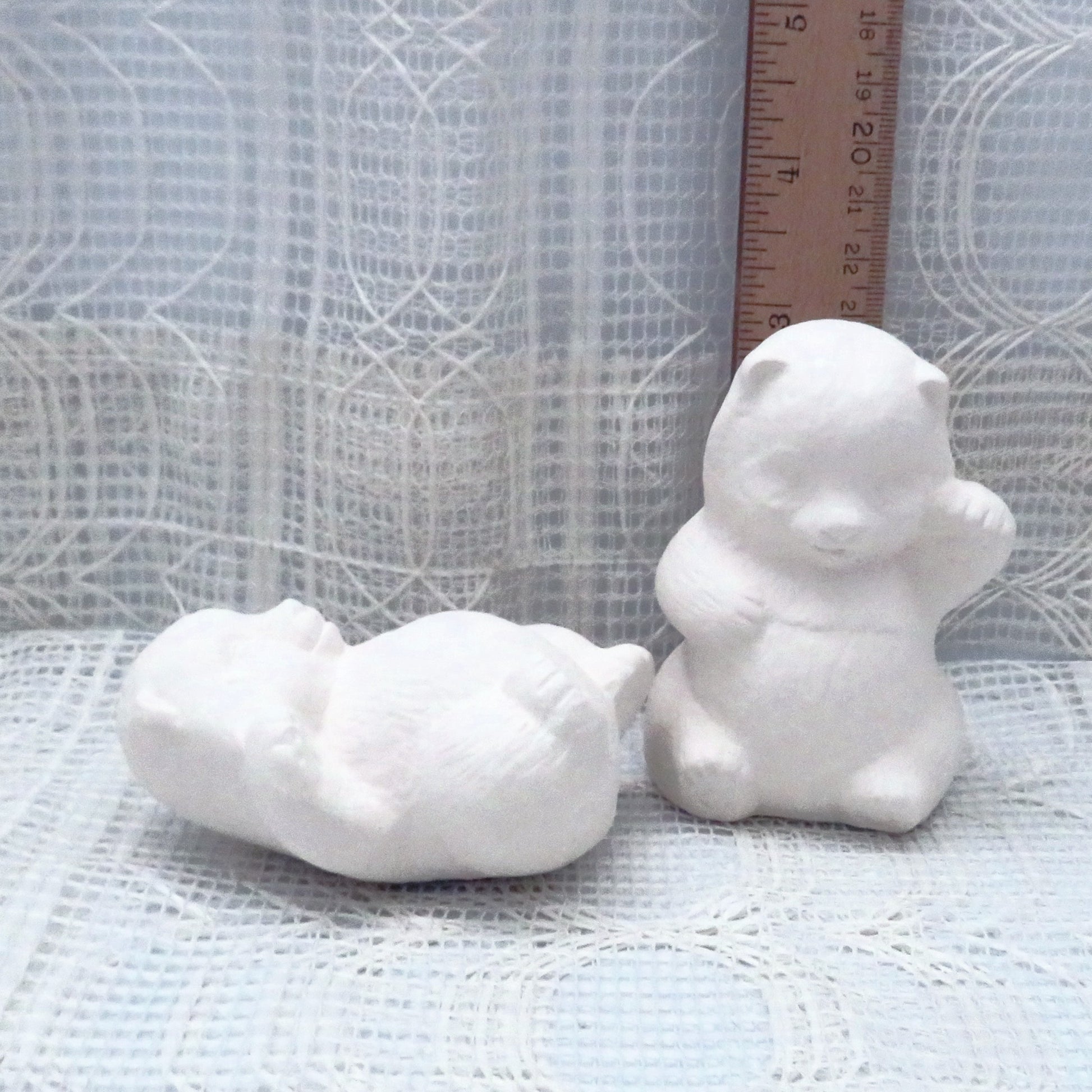 Handmade unpainted ceramic panda statues near a ruler showing the sitting one to be approximately 3 inches tall.