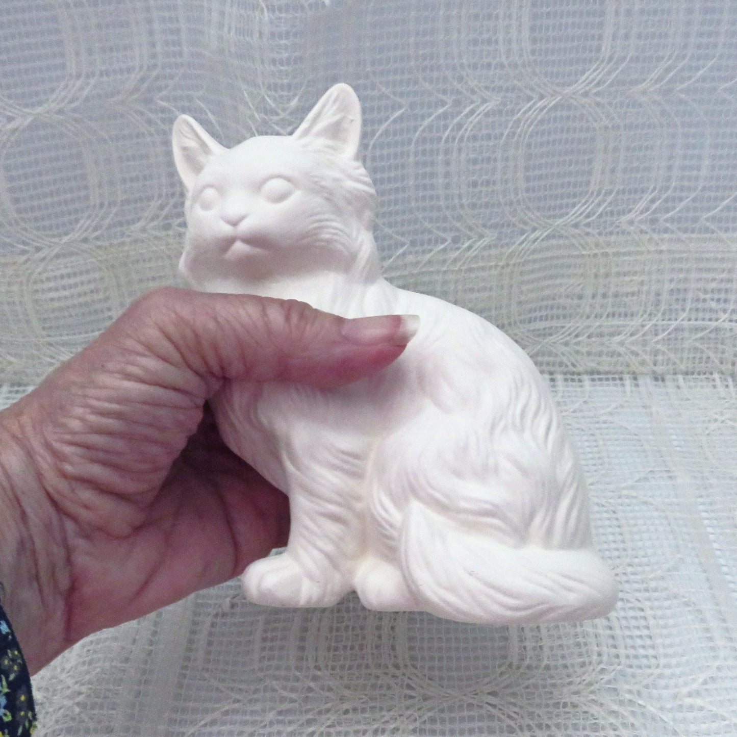 Unpainted ceramic cat figurine in my hand to show size comparison. hand