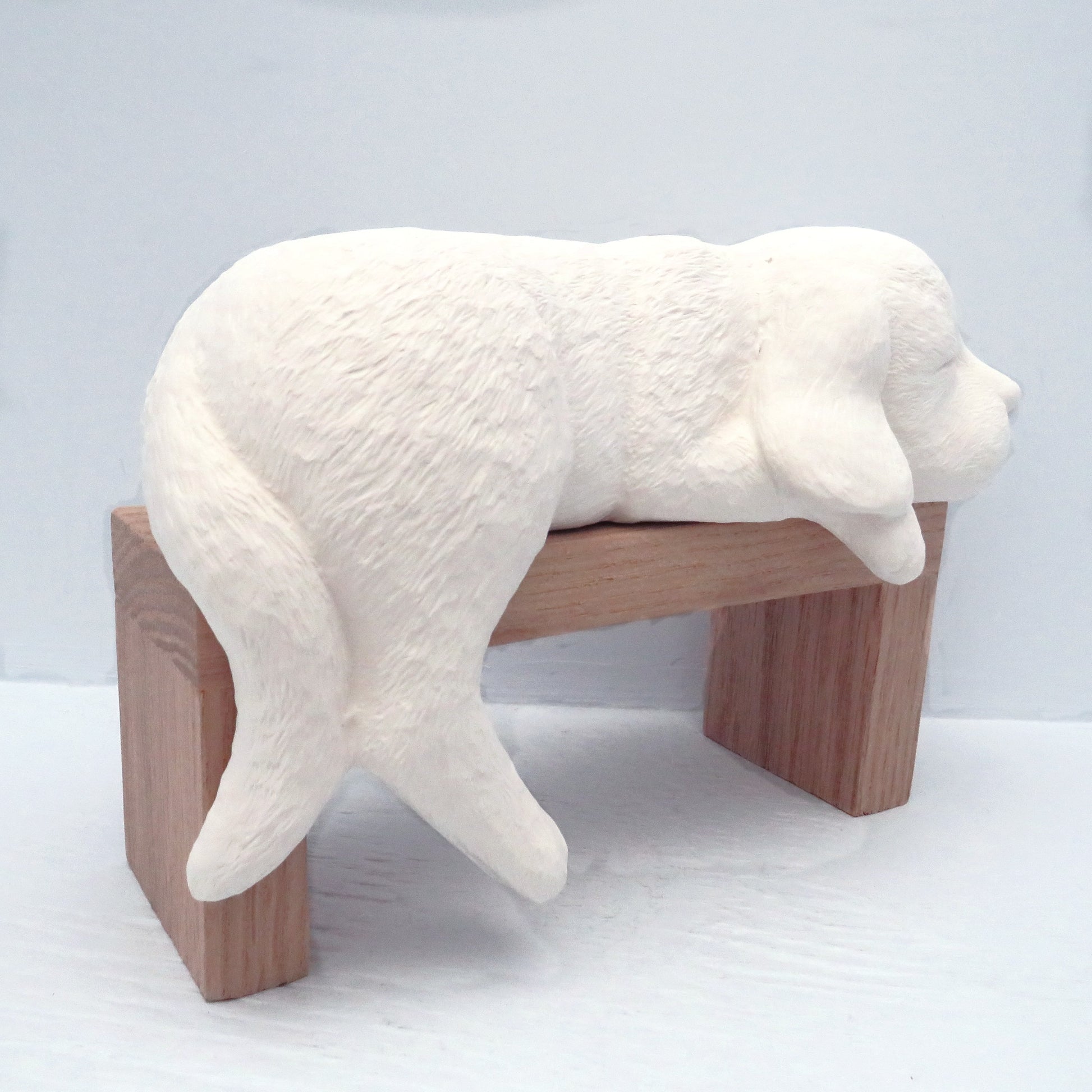 paintable ceramic dog statue on wood pedestal facing away from the camera