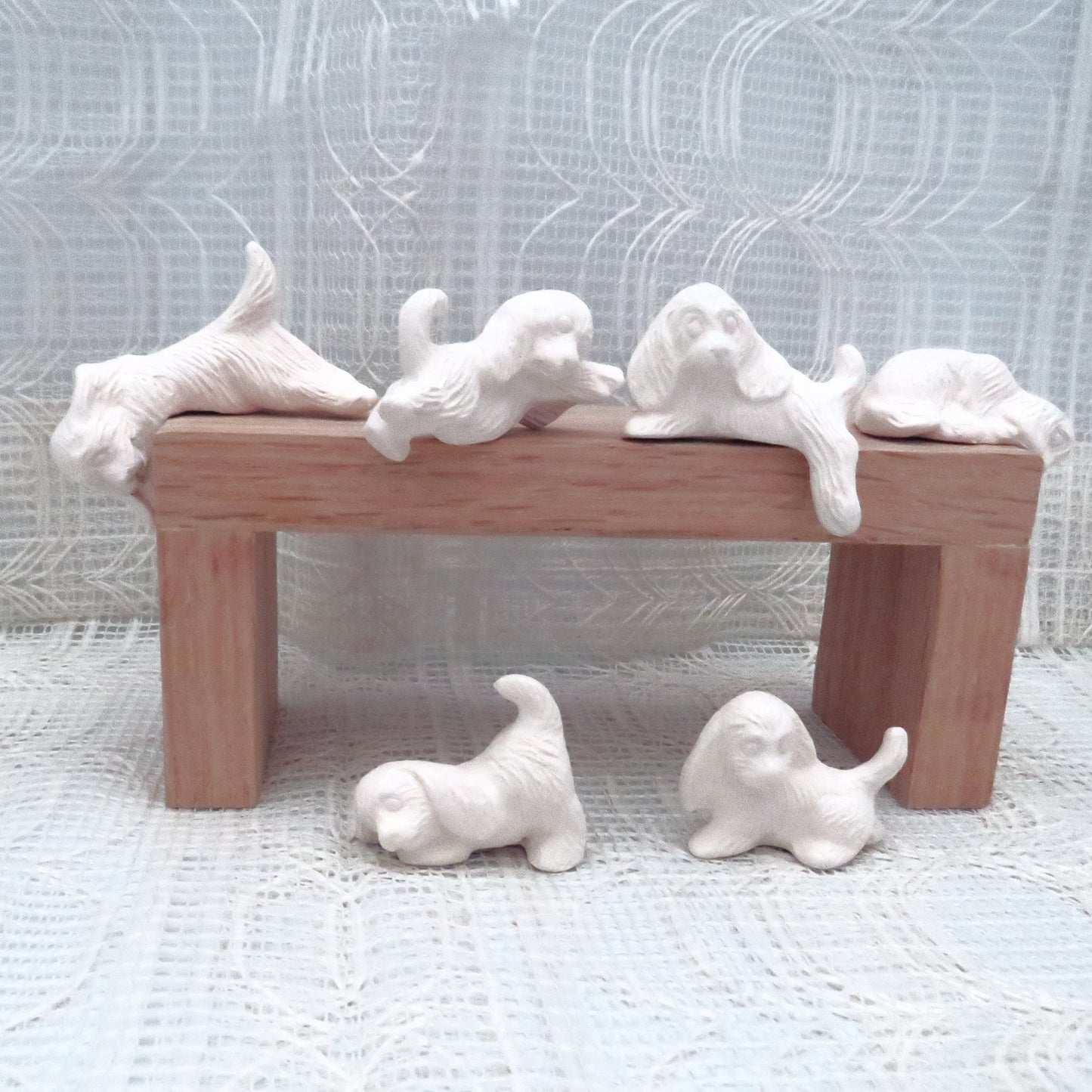 6 small ready to paint ceramic dog figurines on and around a pedestal.