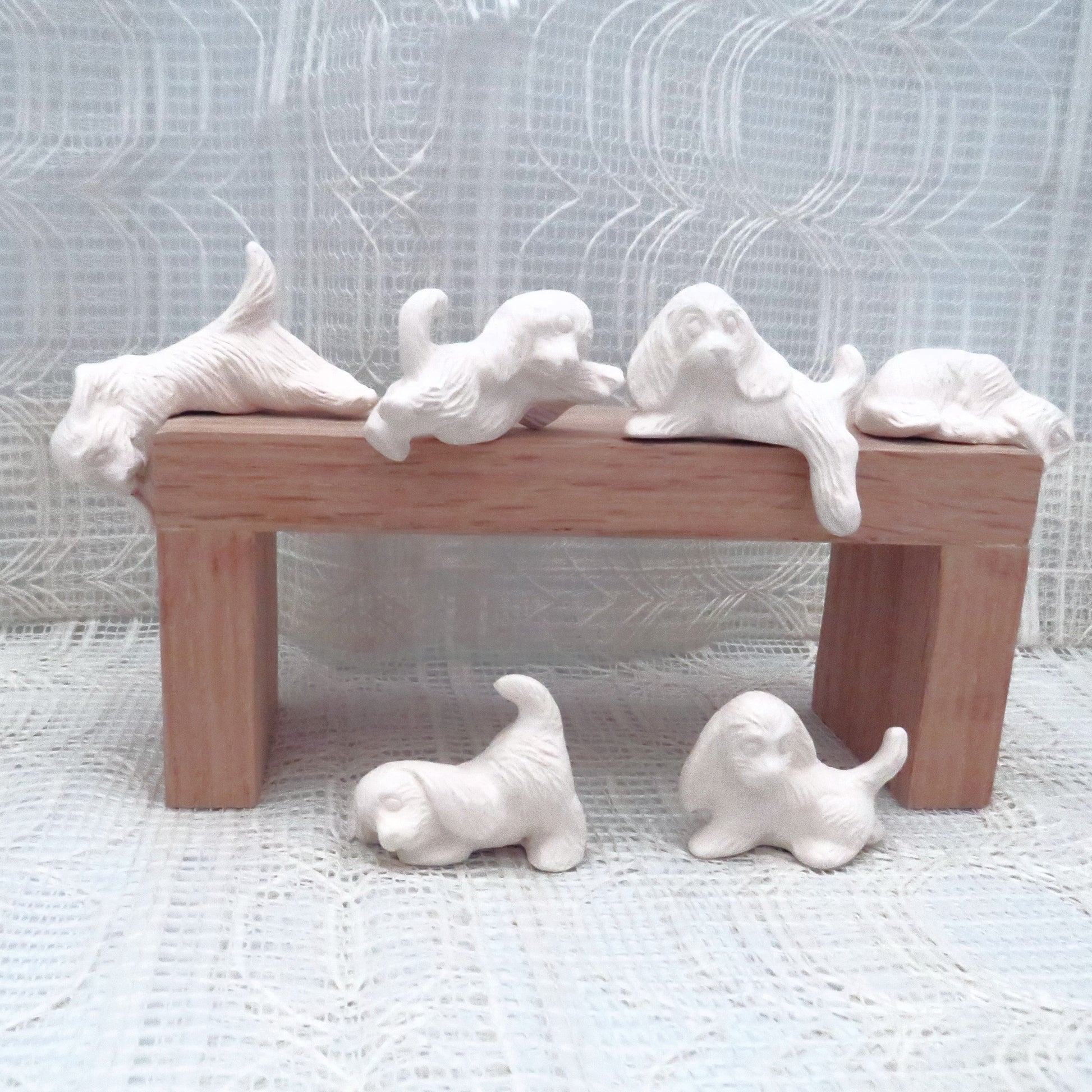 6 small ready to paint ceramic dog figurines on and around a pedestal.
