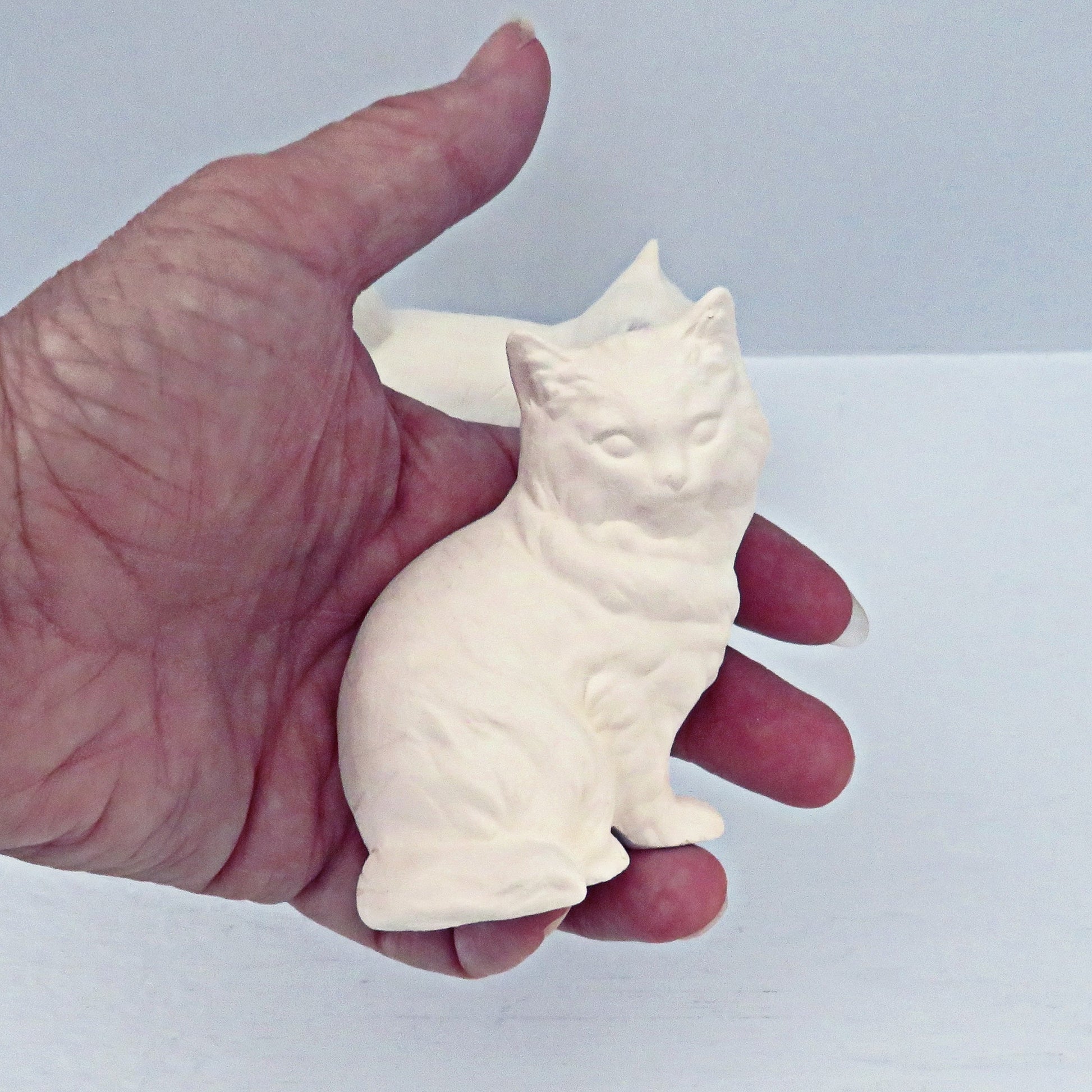 Paintable sitting ceramic cat statue in my hand.