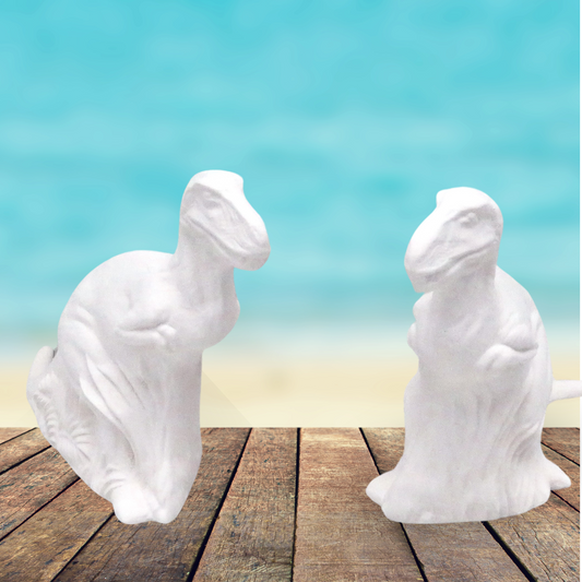 2 ready to paint tyrannosaurus rex figurines standing on a rustic wood table by the beach