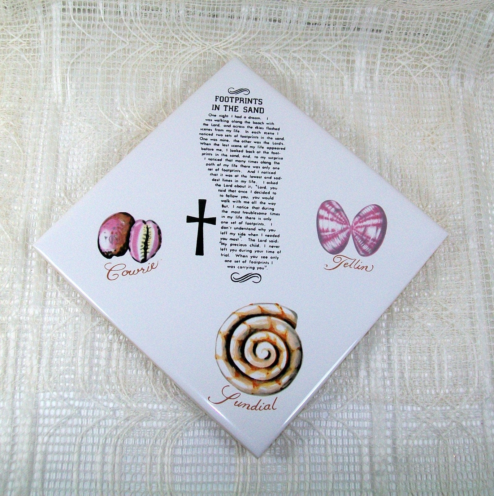 Square white tile positioned diagonally with sea shells, a cross, and the Footprints in the Sand Poem