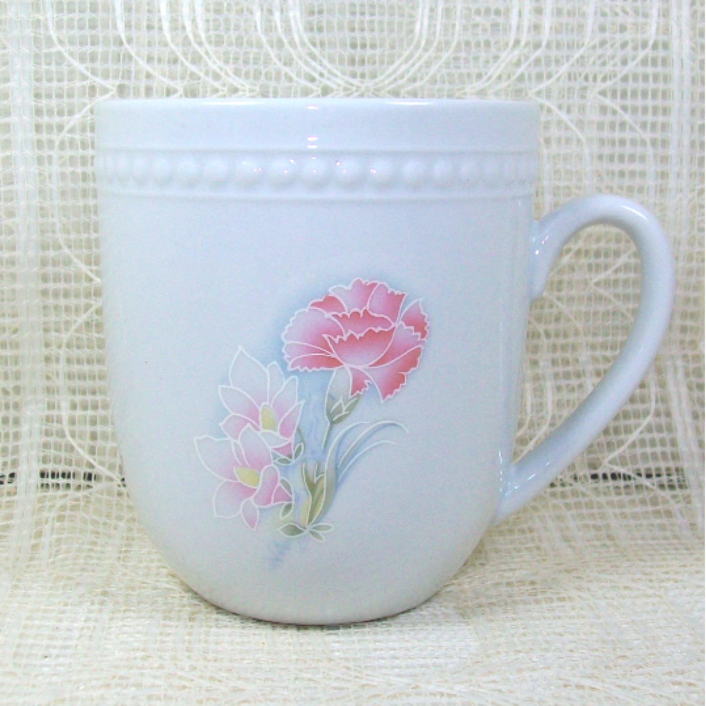 White mug with pink flower on lacy background