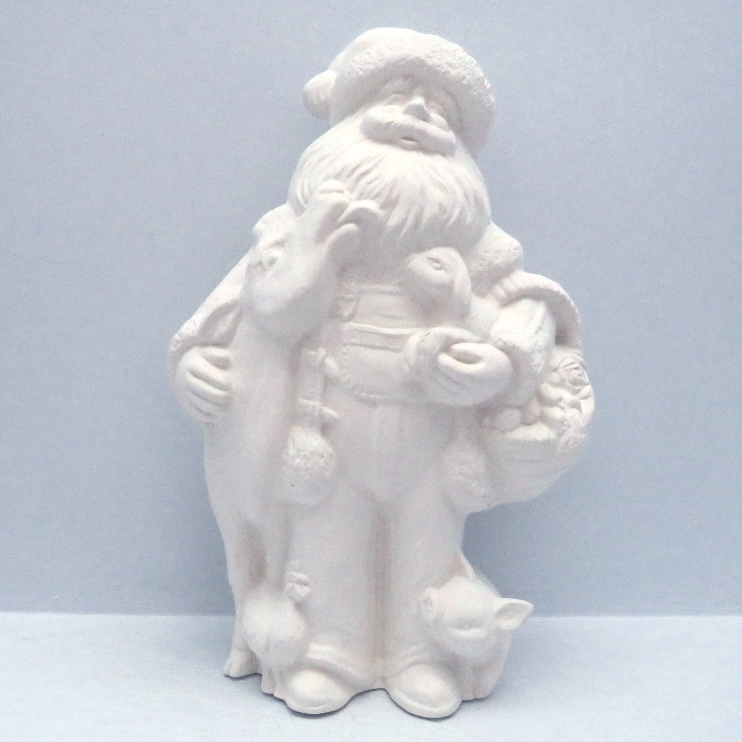 Unpainted Farmer Santa standing with a cow, pig, lamb, on a pale blue surface