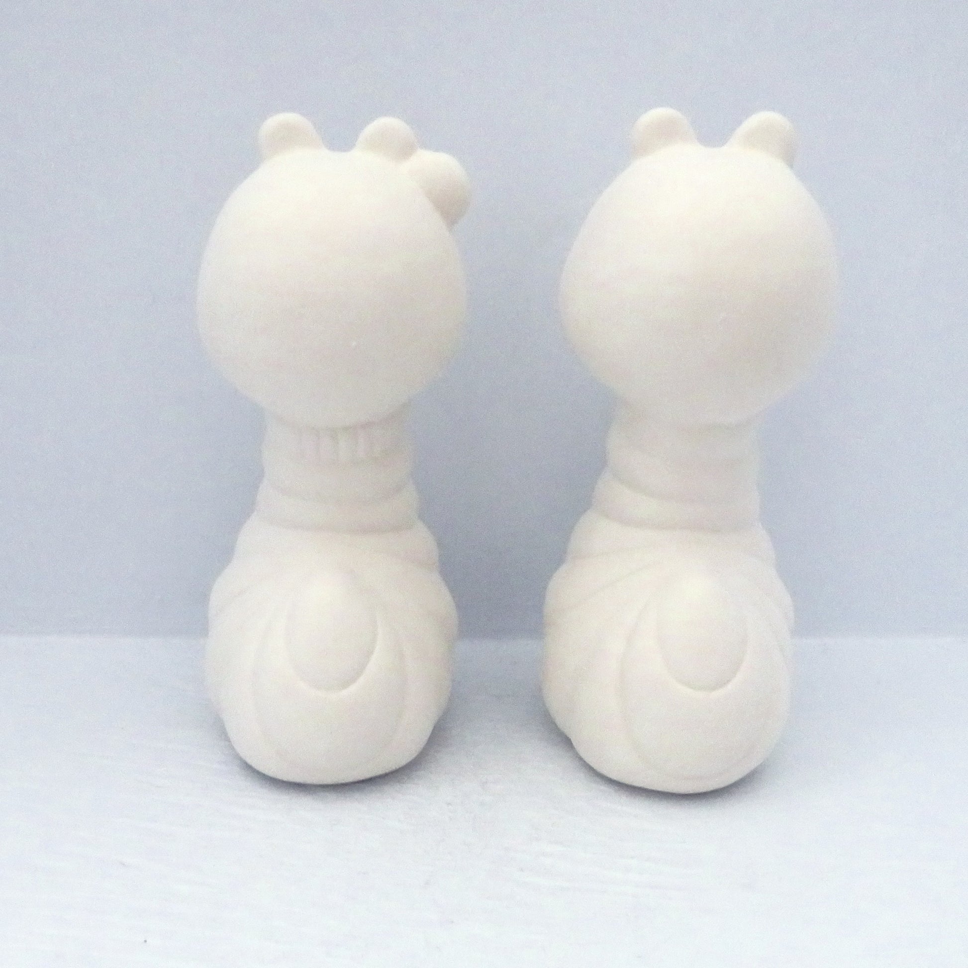 2 paintable ceramic bug figurines back view on a pale blue background