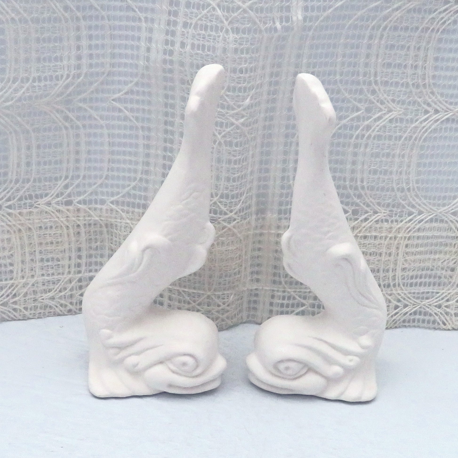 Set of 2 unpainted ceramic fish statues facing each other, giving us a side view.