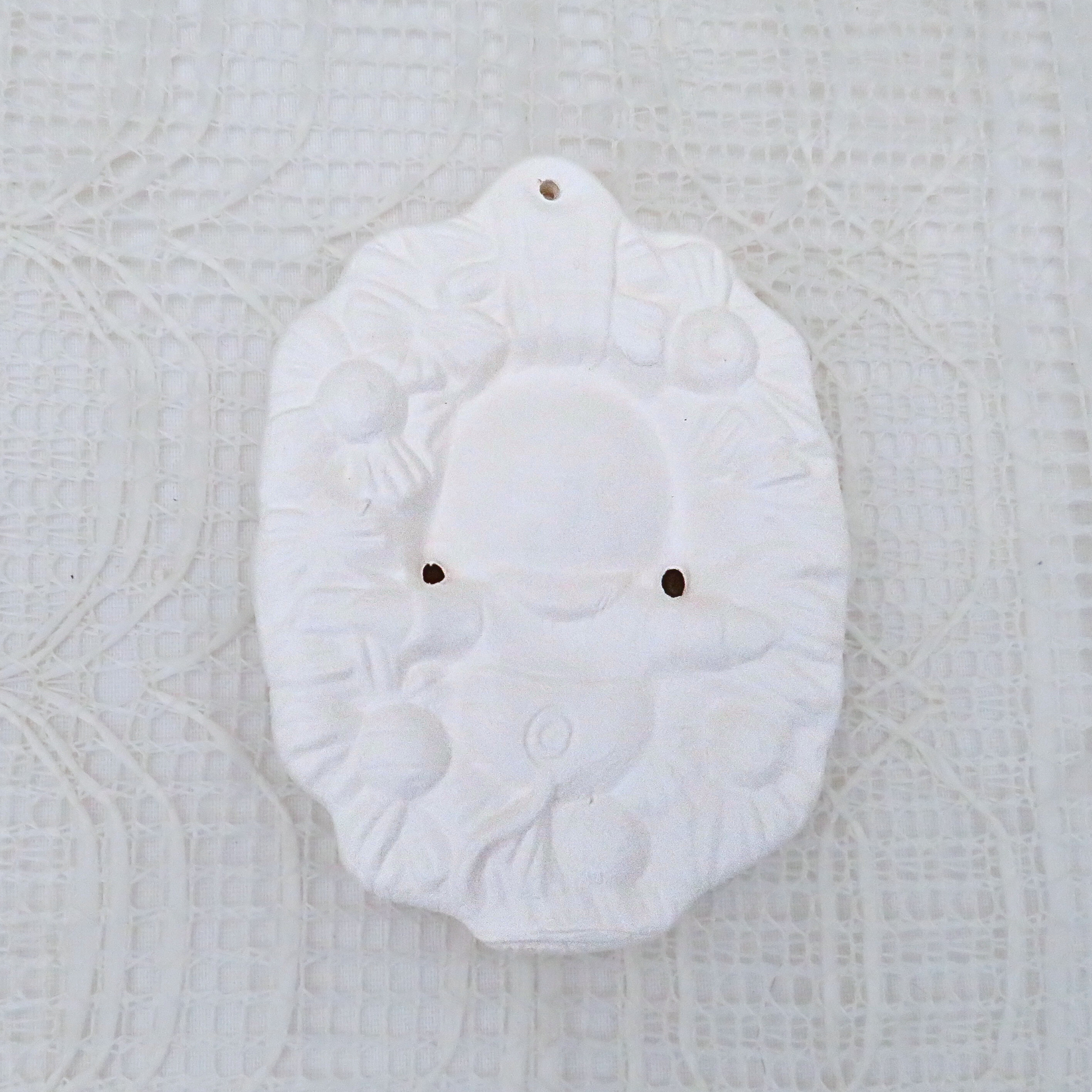 Unpainted ceramic ornament with a mouse sitting in a wreath.  Rear View.