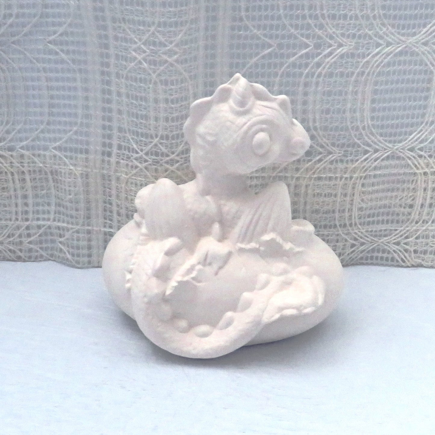 Rear view of ready to paint ceramic baby dragon showing it's wings and tail.