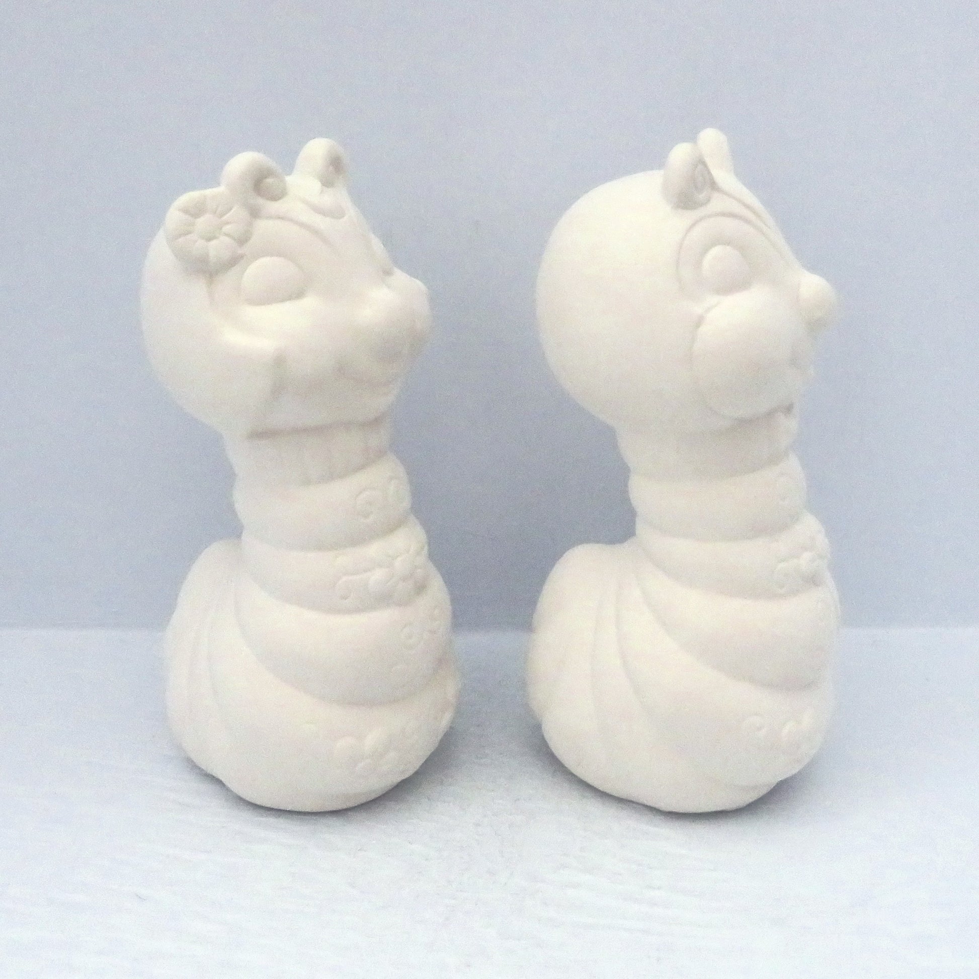 2 ready to paint ceramic bug statues facing to the right on a pale blue background