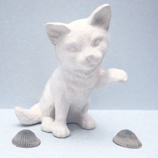 handmade ready to paint ceramic cat with paw up sitting on light blue background  angled front view