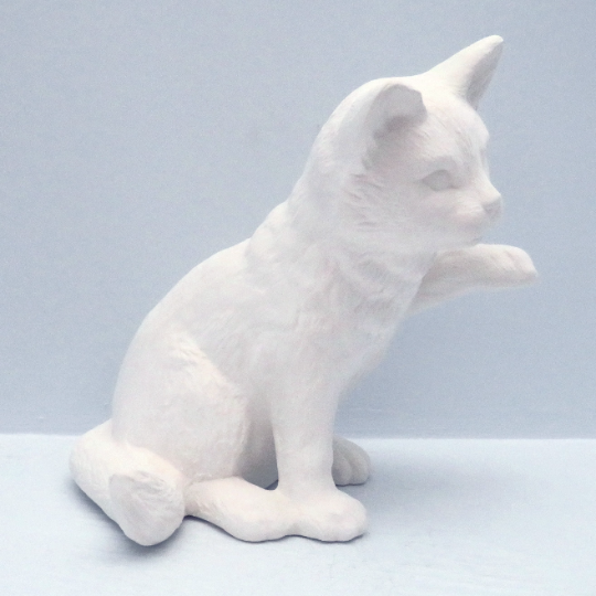 Side view of paintable ceramic cat sitting with left paw up sitting on a light blue background