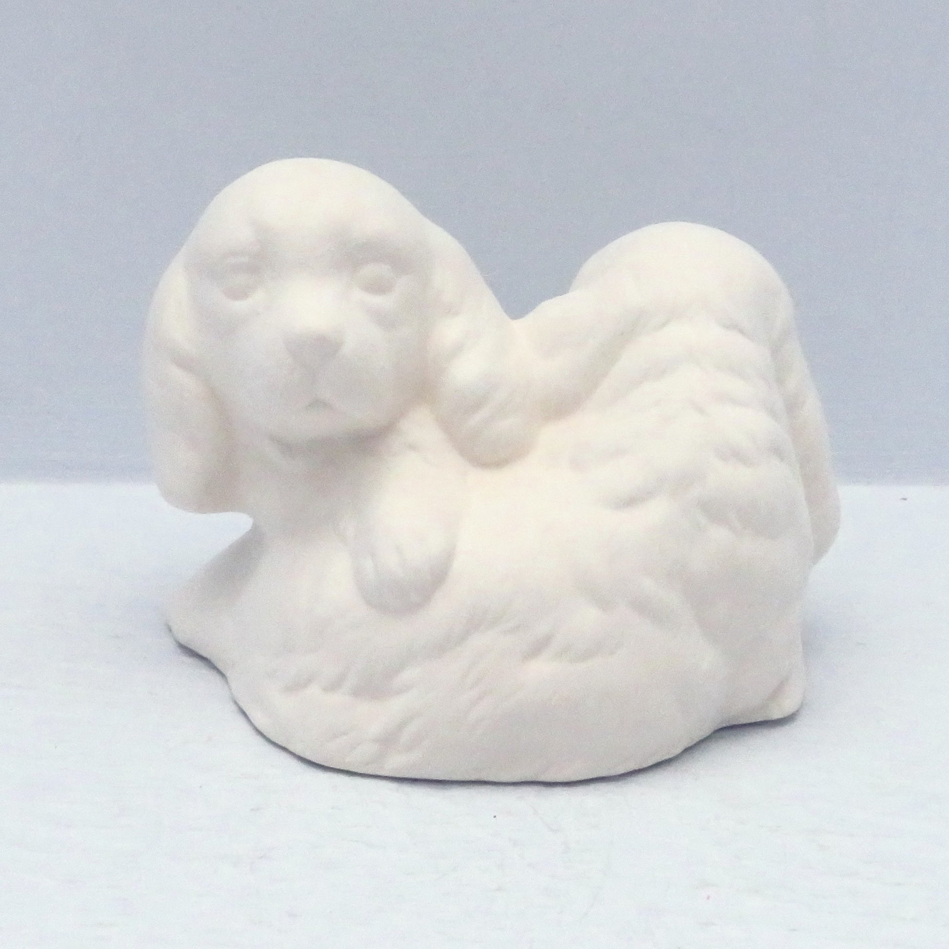 handmade ready to paint figurine with 2 puppies curled over each other.  One is looking forward and one is looking back away from the camera