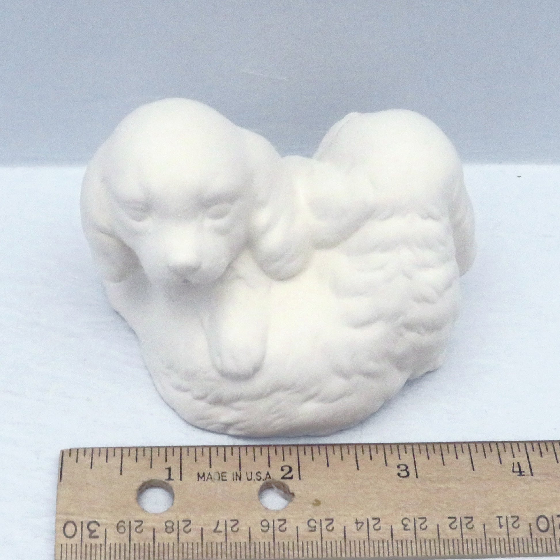 Handmade paint it yourself ceramic figurine with puppies near a ruler showing it to be approximately 3 3/4 inches wide