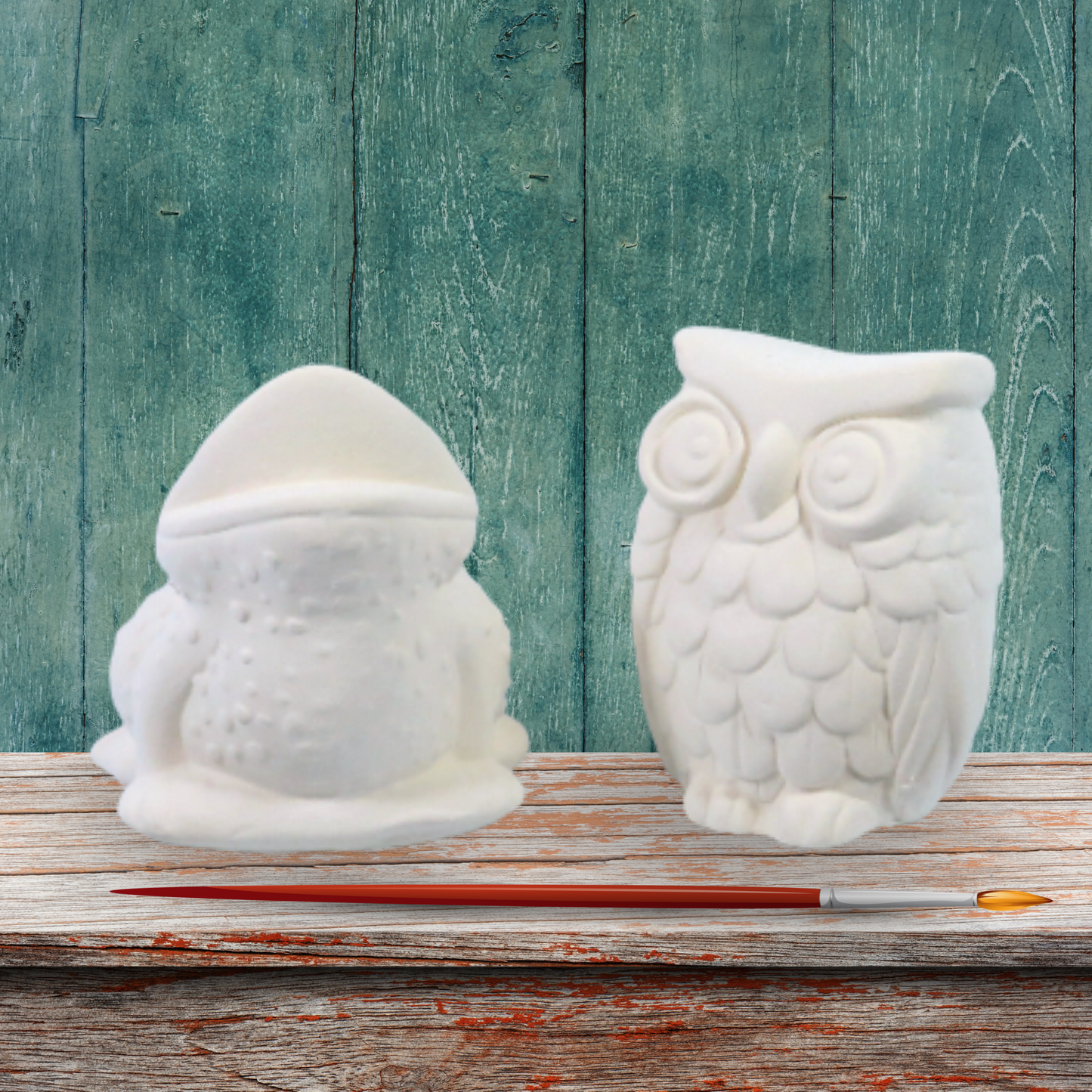 Handmade ready to paint frog and owl figurine set standing on a rustic shelf with a rustic green background.  There is a paintbrush in front of them illustrating that they are to be painted.