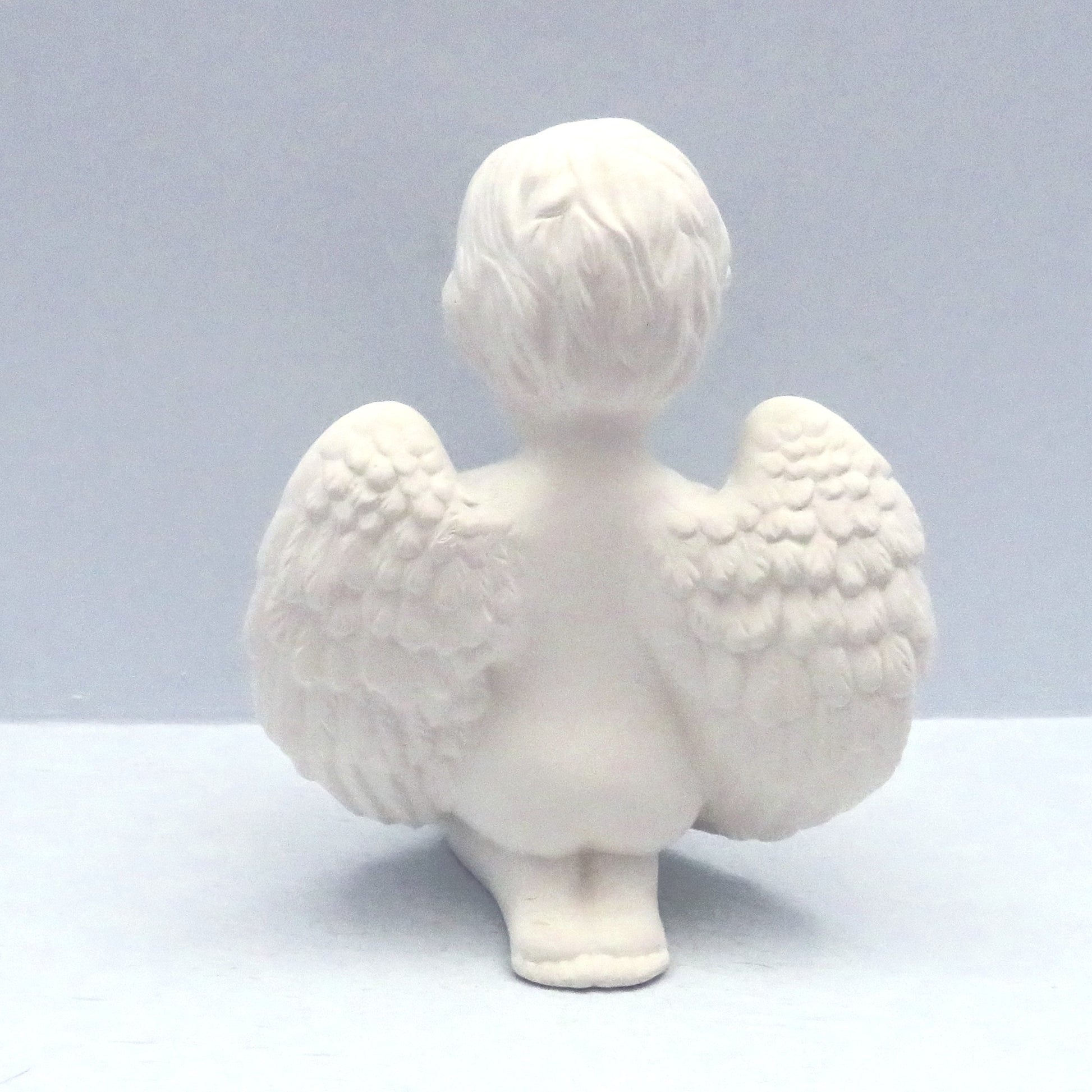 Back view of handmade paint it  yourself ceramic cherub showing wings and feet.