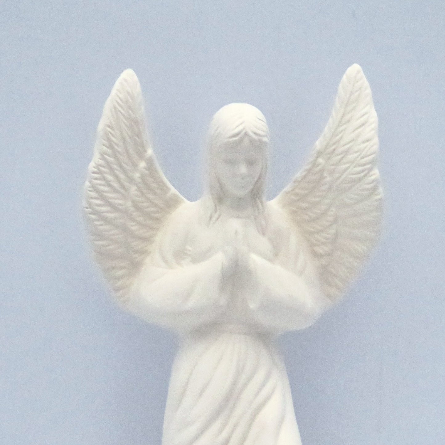 close up of upper section of unpainted praying ceramic angel statue