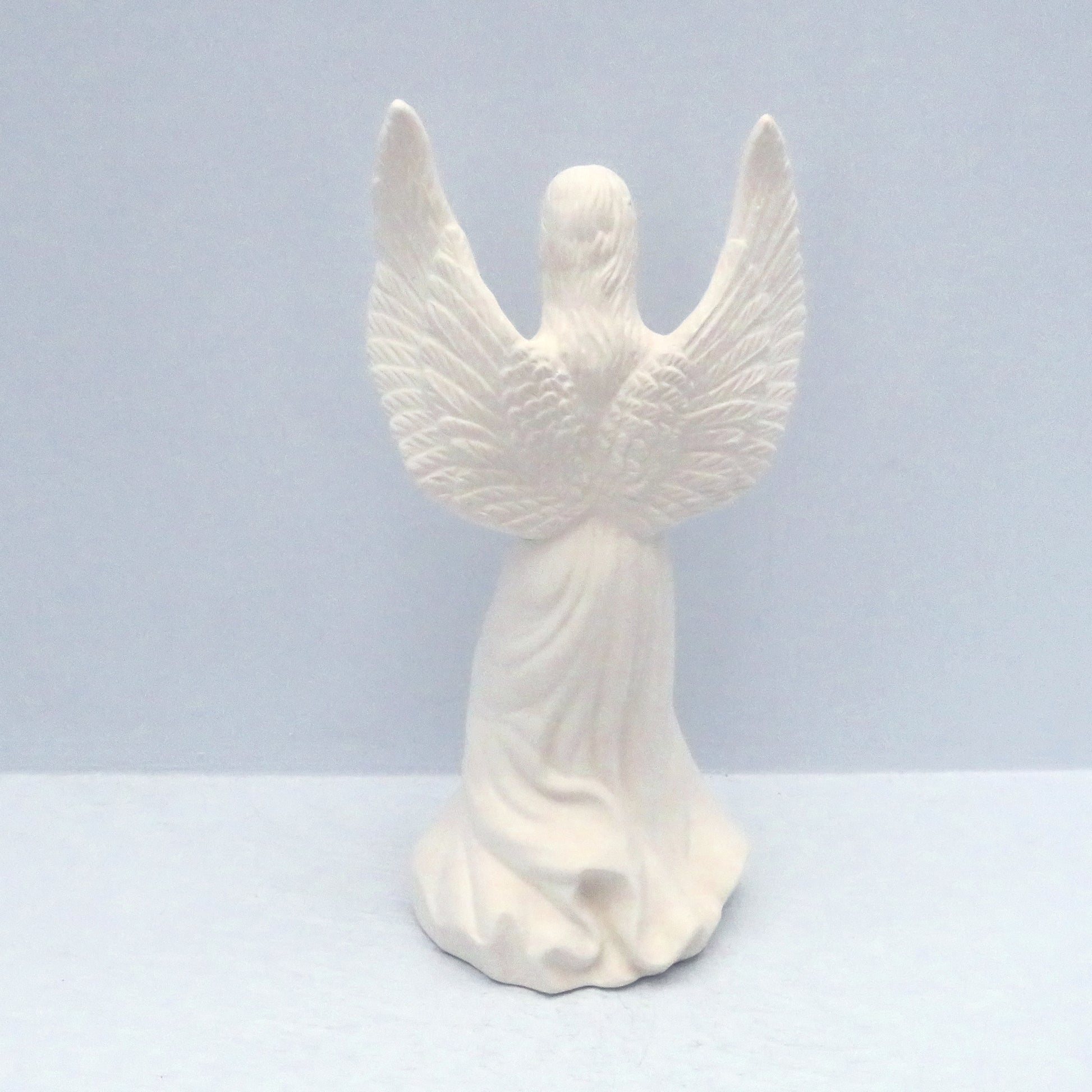 Back of paintable handmade ceramic angel statue showing her wings and long, flowing dress