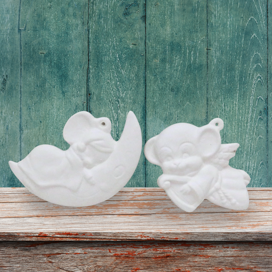 2 ready to paint ceramic Christmas Tree ornaments.  One is a mouse asleep on a moon, one is an angel mouse with a harp.  They are on a shelf with a green background