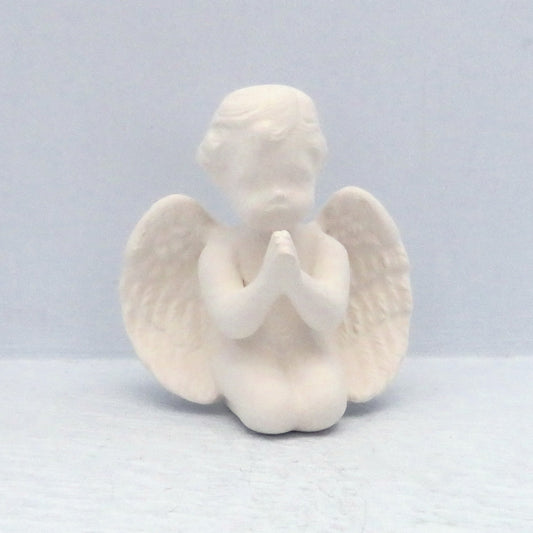Small ready to paint praying ceramic cherub figurine on knees on a blue surface