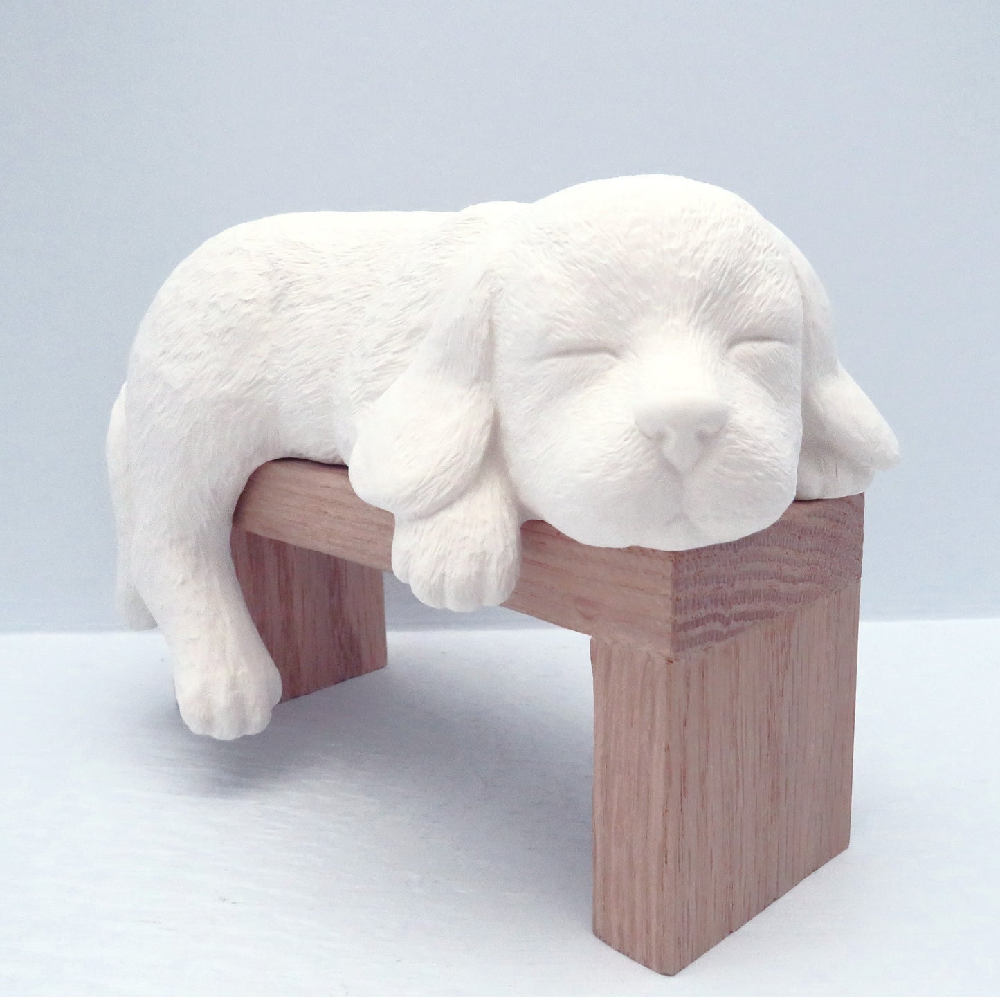 unpainted ceramic dog figurine on pedestal facing camera