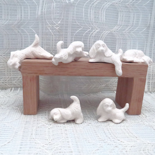 6 small ready to paint ceramic dog figurines on and around a pedestal.