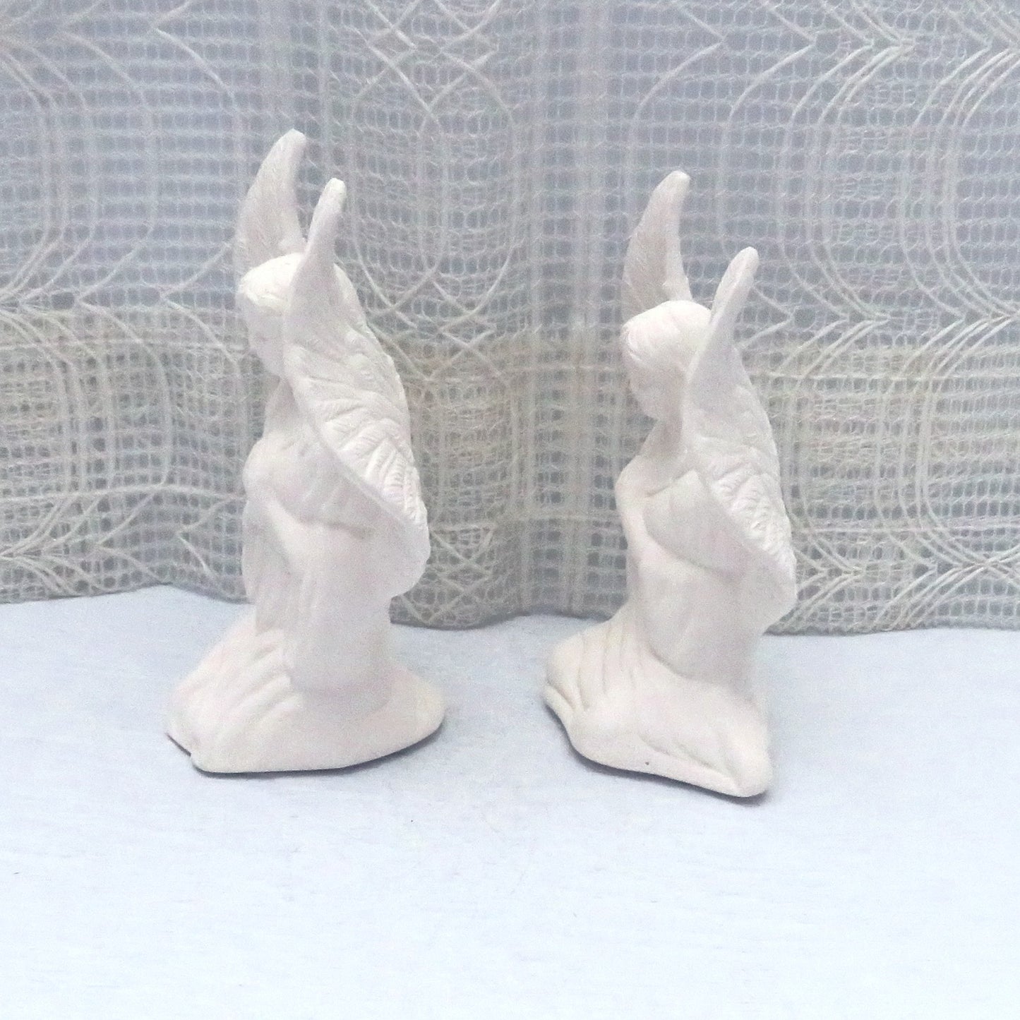 Handmade paintable ceramic angel statuettes facing to the left.