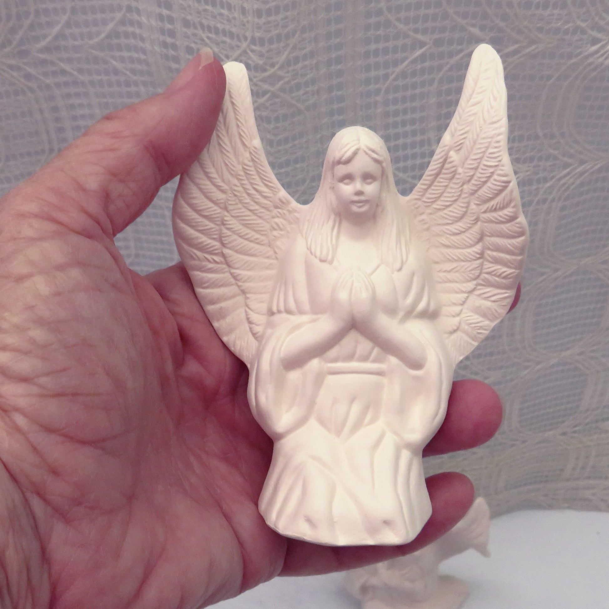 handmade ready to paint ceramic angel figurine in kneeling position with hands in prayer position.