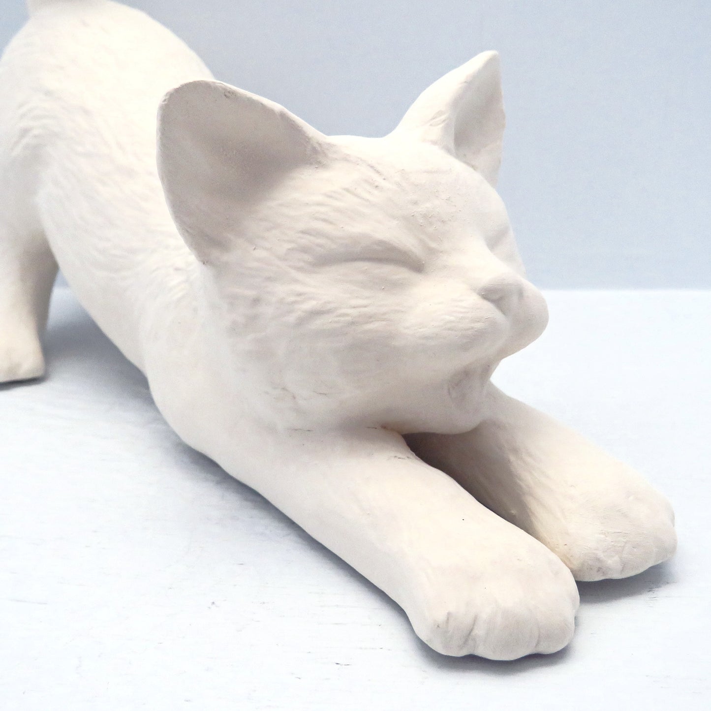 Close up veiw of handmade paintable stretching cat's face.  Its mouth is open and its eyes are closed.