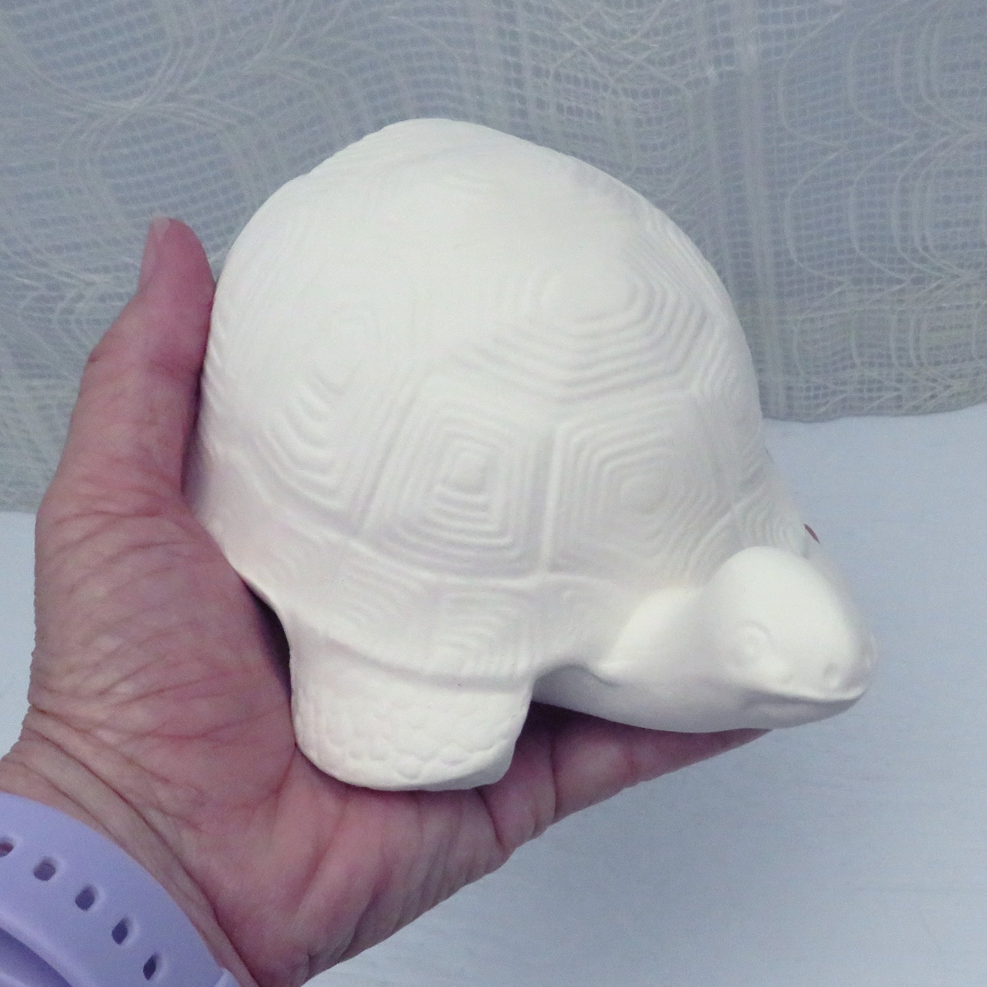 Ready to paint ceramic turtle in my hand illustrating size.