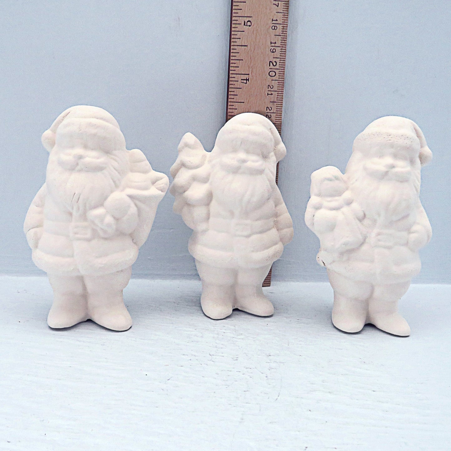Set of 3 Santas facing forward in front of a ruler, showing them to be approximately 3 inches tall