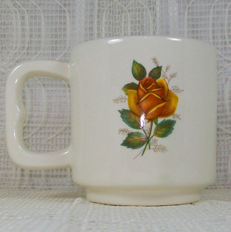 One single mug with the handle toward the left, showing the yellow rose
