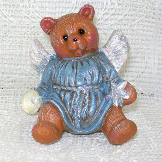 Small Teddy Bear Angel with a Blue Tunic and glitter wings holding a clear stone.
