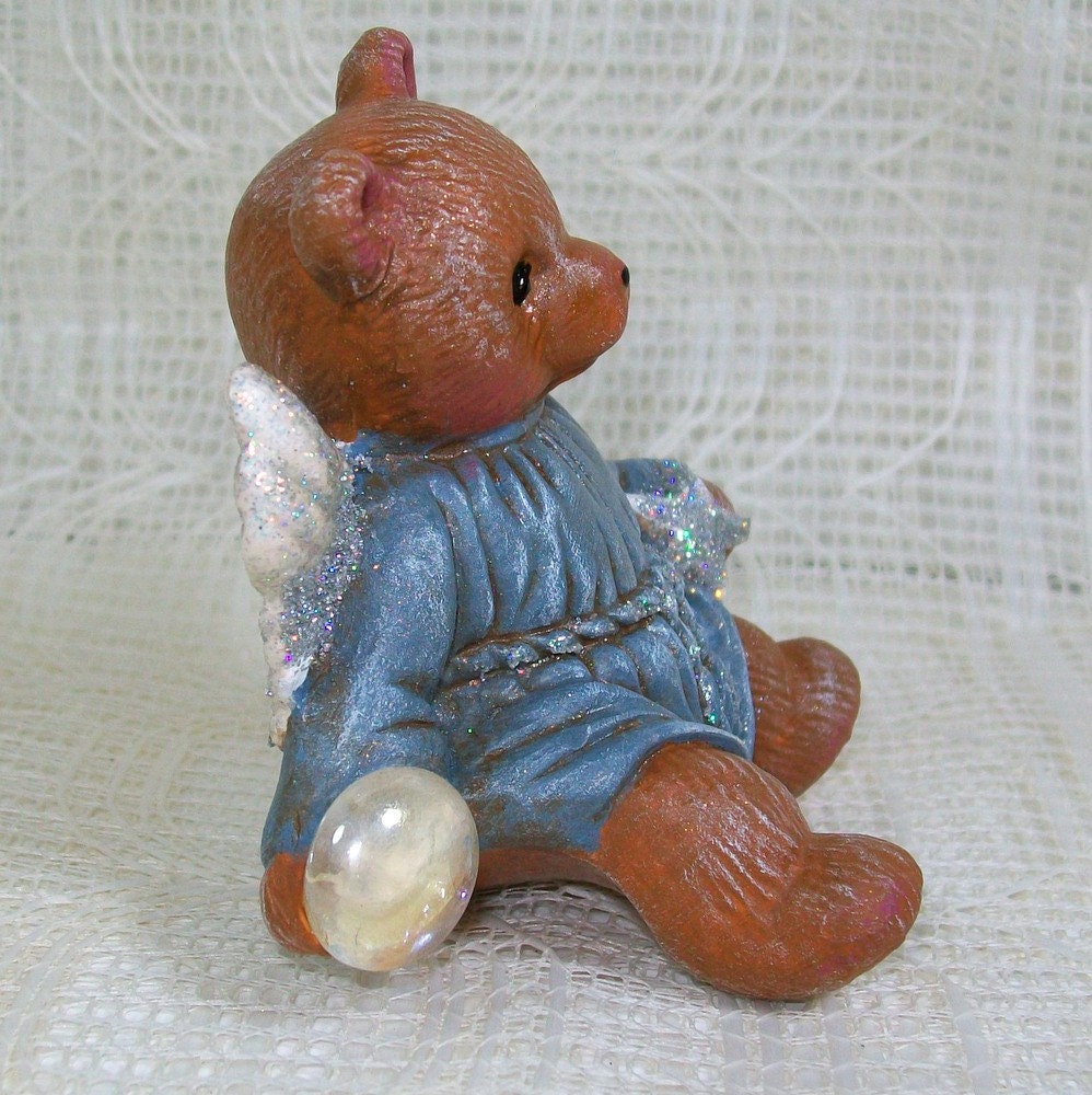 Side view of brown angel bear holding a clear stone
