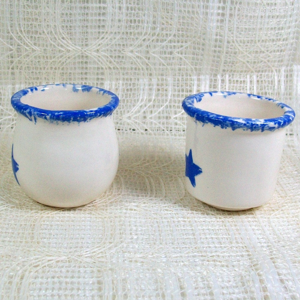 Side view of 2 glossy white handmade ceramic votive candle holders sitting on a lacy background